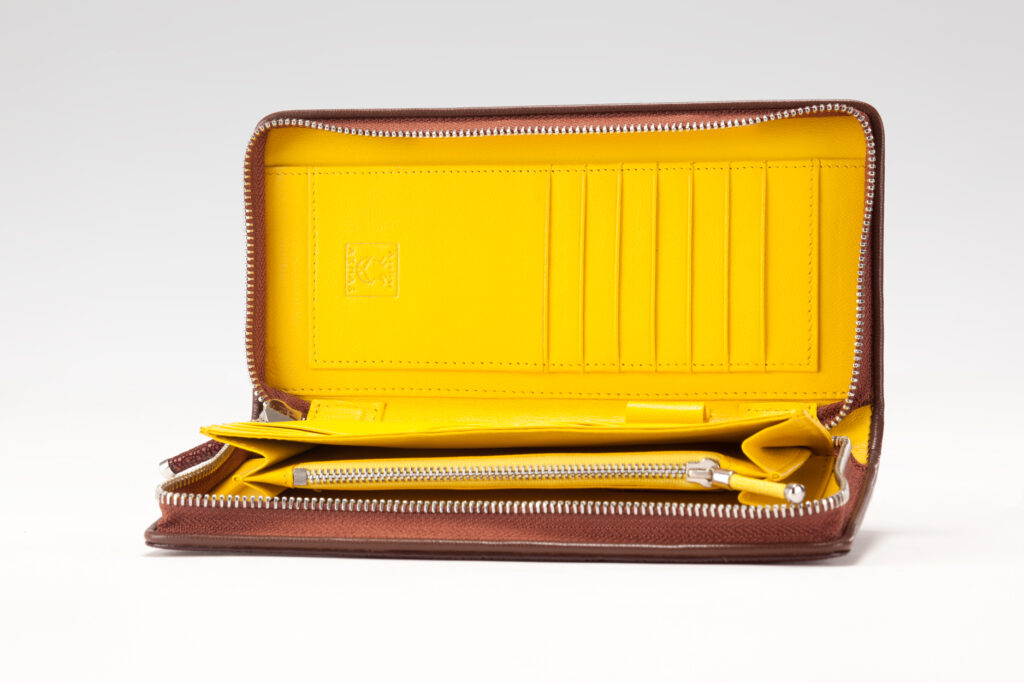Open brown stingray leather zip-around wallet by AKNAS featuring a bright yellow interior, multiple card slots and a zippered coin compartment.